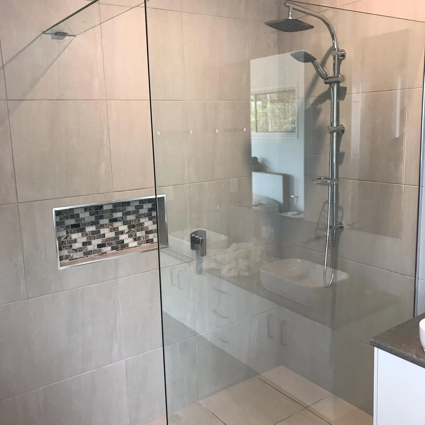 Frameless shower screen beside a tiled niche — gallery shower frameless niche