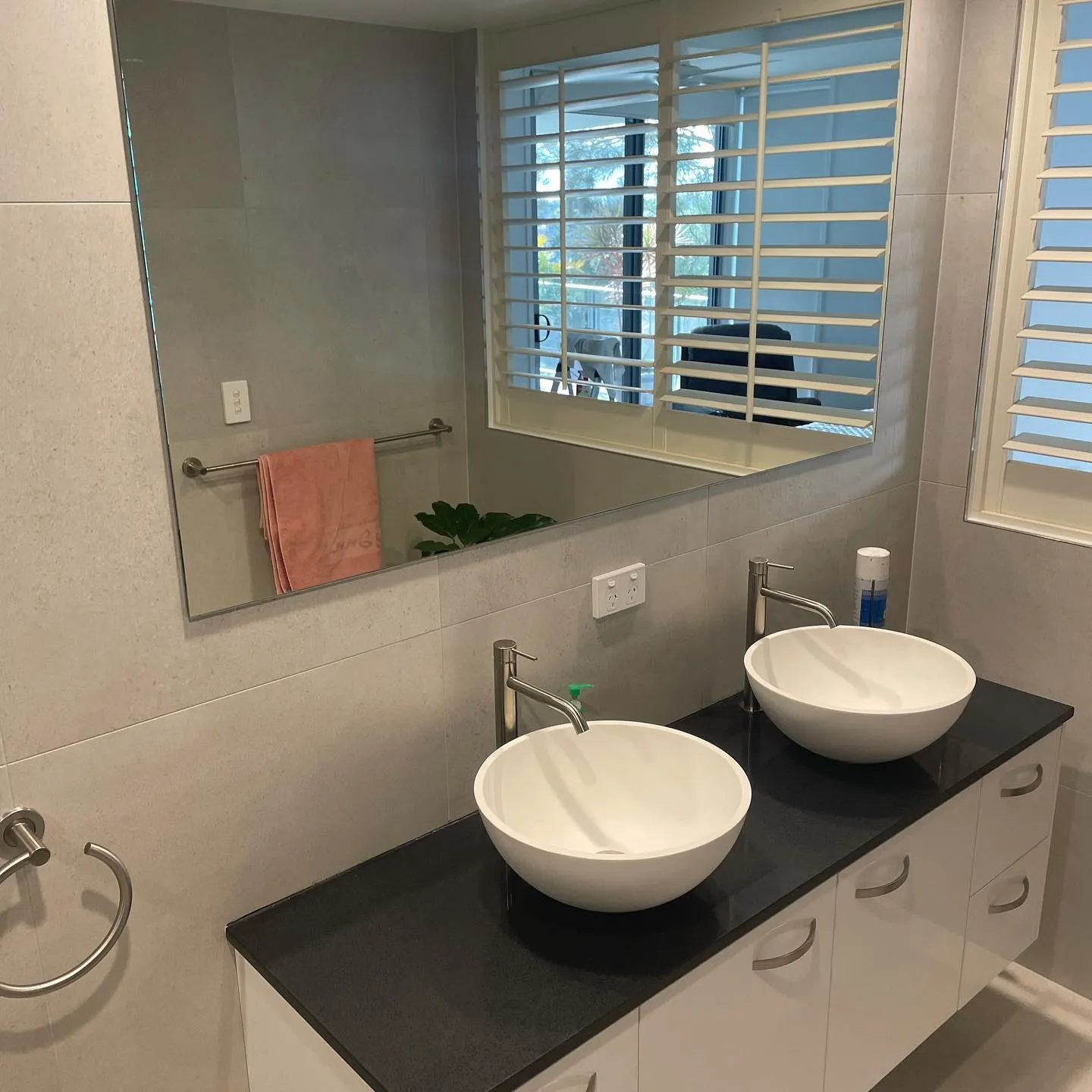 Frameless mirror above a vanity in a renovated bathroom